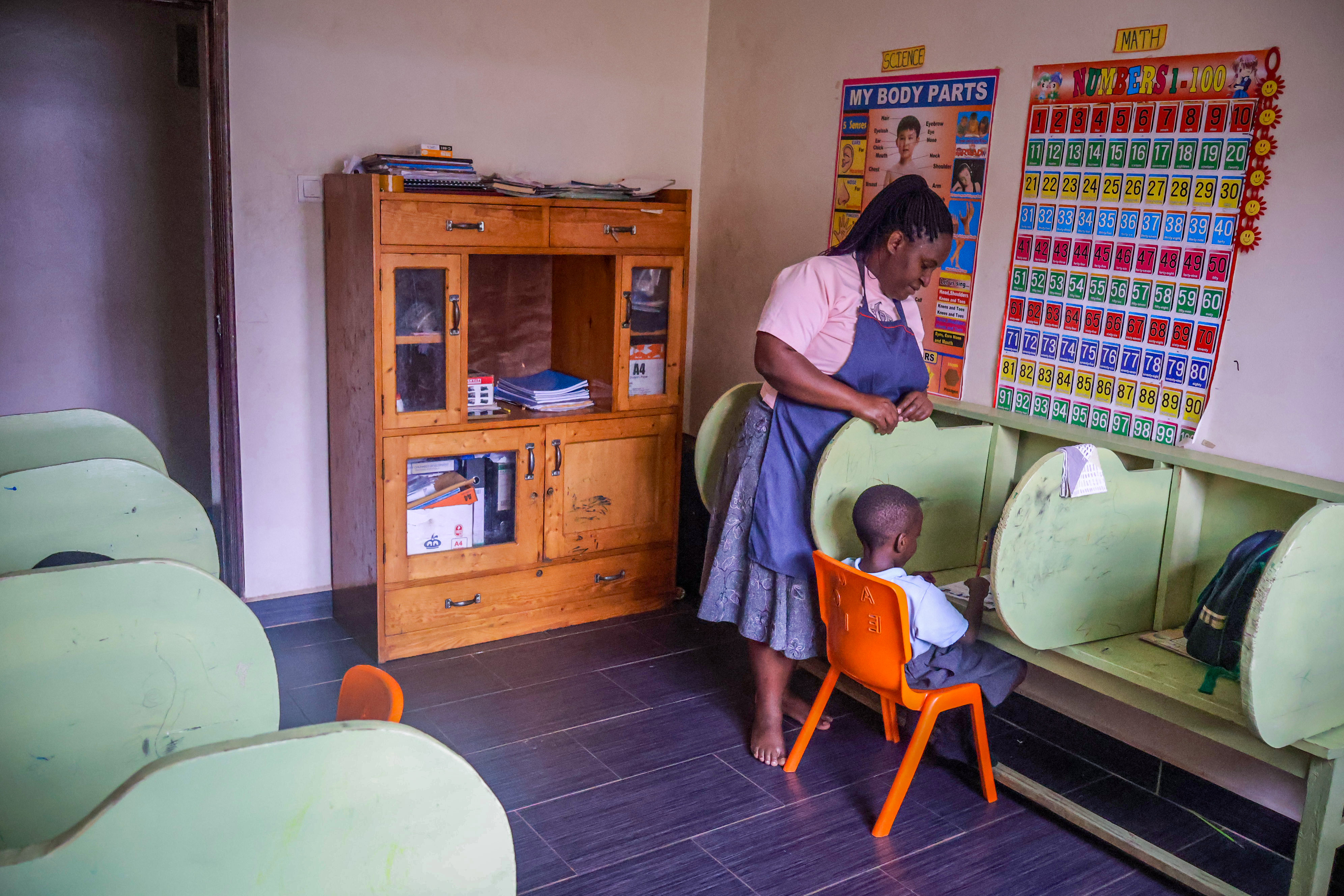Teacher assisting a learner seated at a reading booth